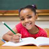 Student girl writing with a green pen and smiling