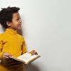 Boy talking with somebody while holding a book in his hands