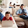 Father using tablet, son using laptop while lying on the coach