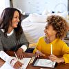 Mother and daughter writing and laughing while watching each other