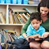 Mother and son reading a book while sitting on the ground