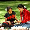 Mother and daughter sitting on the grass and reading a book