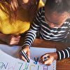 Mother assisting daughter learn writing