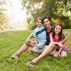 Father and two children sitting on the grass and smiling