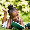 Girl reading a book while lying on the grass