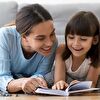 Mother and Daughter Lying on the Ground While Reading Together